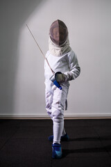 A girl in a fencing suit with a sword in hand. Young female model practicing and exercising....