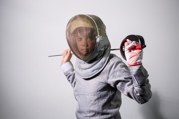 A girl in a fencing suit with a sword in hand. Young female model practicing and exercising....