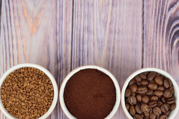 Top view of three coffee cups filled with instant coffee, ground coffee and whole grain coffee.
