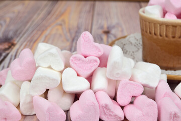 In the foreground there is a marshmallow slide in the shape of pink and white hearts. A mug filled with the same marshmallows is visible in the background.