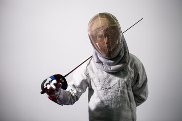 A girl in a fencing suit with a sword in hand. Young female model practicing and exercising....