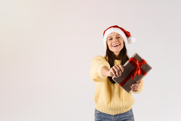 Christmas concept. Young beautiful woman hold christmas gift wearing red hat. Smiling happy girl on white background