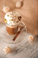 Pumpkin latte in a transparent mug close-up and copy space. Latte with cream, cinnamon, pumpkins, pumpkin seeds on a white plate. Latte and sweater.