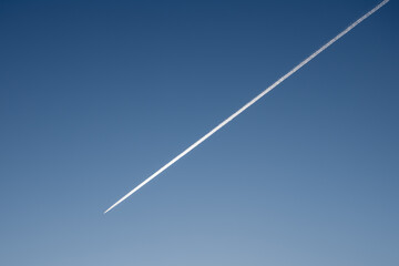 White condensation trace of jet airplane in deep blue sky