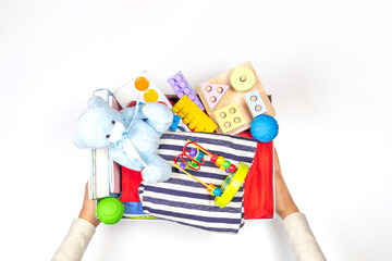 Donation charity concept. Hands holding donate box with clothes, books, school supplies and toys on white background