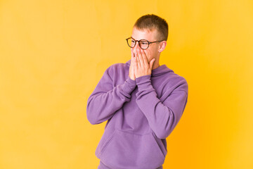 Young caucasian handsome man laughing about something, covering mouth with hands.