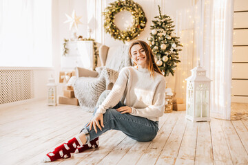 Beautiful cheerful happy young girl with christmas gifts on the floor near the new year tree at home