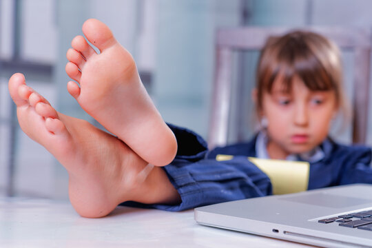 Humorous photo of tired beautiful young business girl with bare feet on the desk in office.