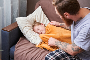 Father covered with a blanket his sick little daughter