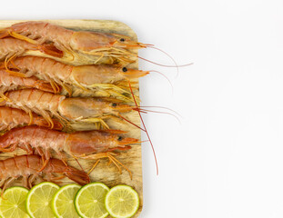 prawns on a wooden cutting board with pieces of lime
