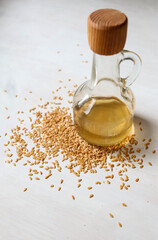 Flax seed oil in a glass bottle with seeds spread around.