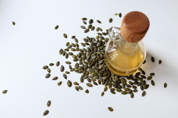 Raw papitas - no shell pumpkin seeds and pumpkin seed oil bottle on white.
