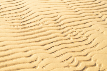 Gold sand with abstract wave pattern. Background of sea shore texure. Summer and vacotion concept. Top view, copy space.