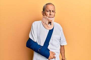 Handsome mature senior man wearing cervical collar and arm on sling depressed and worry for distress, crying angry and afraid. sad expression.