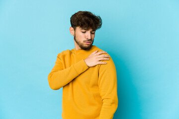 Young arab man on blue background having a shoulder pain.