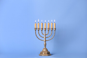 Golden menorah with burning candles on light blue background, space for text - obrazy, fototapety, plakaty