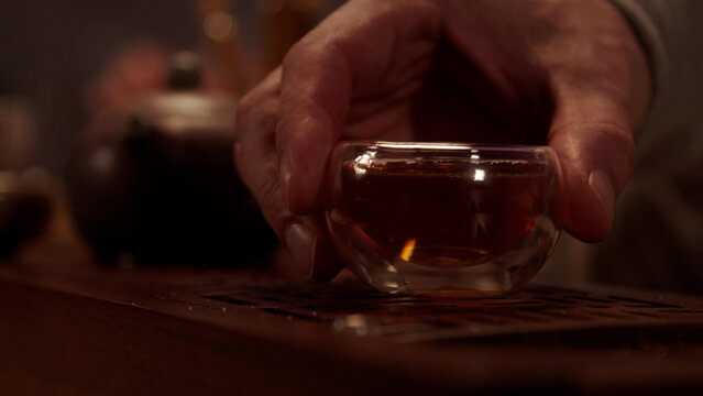The hospitable host treats the guest to delicious Japanese tea from a glass bowl. Close-up without a face.