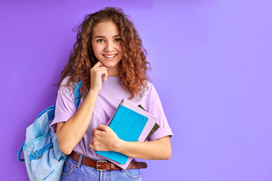 sweet caucasian friendly young student girl holding colorful exercise books, ready to study