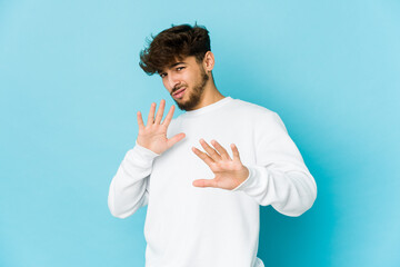 Young arab man on blue background rejecting someone showing a gesture of disgust.