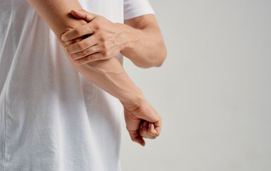 a man touches his wrists on a light background and a white t-shirt