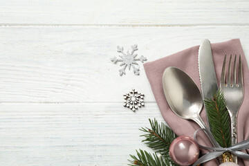 Cutlery set and festive decor on white wooden table, flat lay with space for text. Christmas celebration