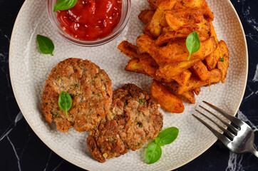 Masala chips on a white plate with tomato sauce and cutlets, on a dark marble table.