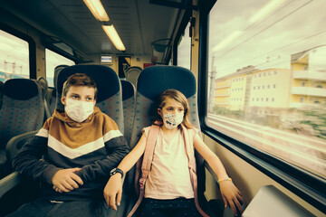 Deux jeunes enfants partant en voyage en vacances en train avec des masques contre la covid-19