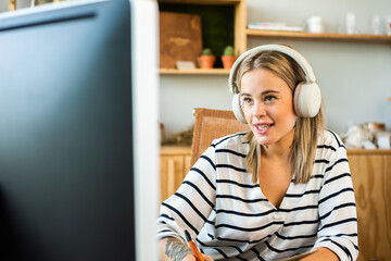 Chica rubia estudiante. Videollamada, atención al cliente. Mujer con cascos modernos blancos de...