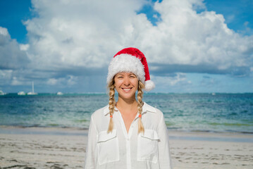 Obraz premium Girl with pigtails and New Year's red hat on the beach