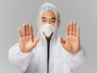 a man in protective medical clothing holds his hands in front of him stop infection treatment