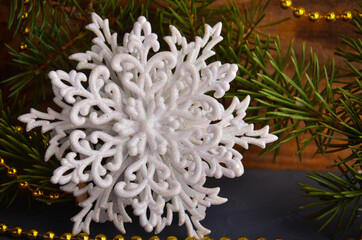 Fototapeta na wymiar White snowflake with fir branches on a background of concrete and wood.