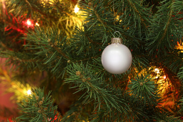 Glowing fairy lights and beautiful bauble on Christmas tree, closeup