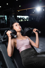 Fototapeta na wymiar young, sportive woman training on arms extension machine in gym
