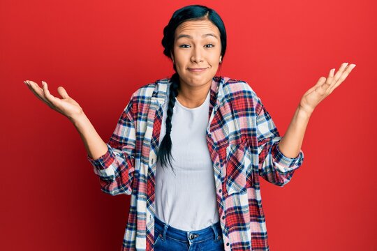 Beautiful hispanic woman wearing casual clothes clueless and confused with open arms, no idea and doubtful face.