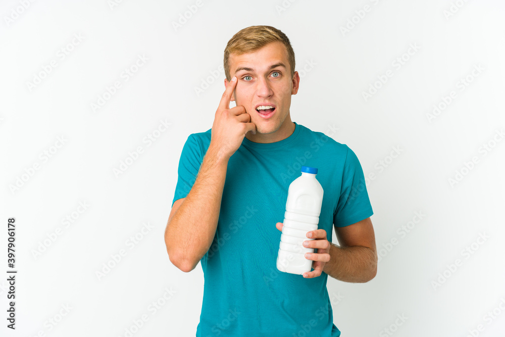 Wall mural young caucasian man drinking milk isolated on white background