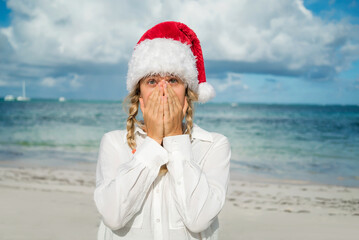 Obraz premium Girl with pigtails and New Year's red hat on the beach. Covers face