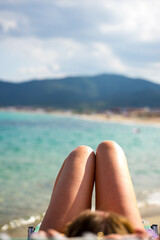 Girls sausage shape legs on the beach in Greece with blurred background sea 