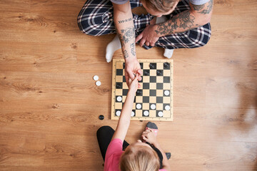 Father and his blonde daughter playing checkers