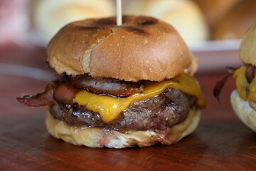 Hamburger. Made on the barbecue grill. With cheese, bacon, onion, pickle. On wooden background