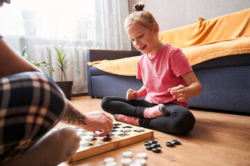 Father and his blonde daughter playing checkers