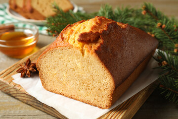 Delicious gingerbread cake and fir branch on wooden table, closeup