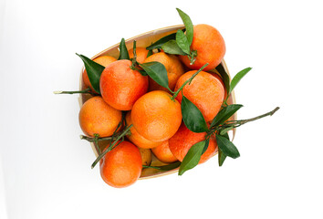 Extra sweet and juicy Spanish clementines with leaves in a basket. Isolated on white. Top down view.