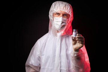 mature doctor man holding vaccine in tube against coronavirus infection, siolated over black background