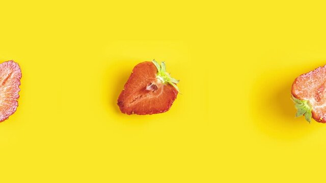 Many red fresh cut strawberry animated on a yellow background. Seamless looping food, minimal motion design art with fruit