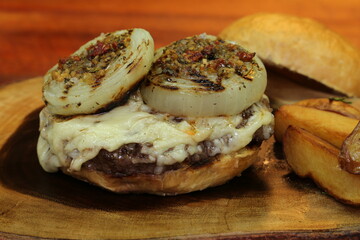 Hamburger. Made on the barbecue grill. With cheese, bacon, onion, pickle. On wooden background