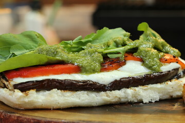 Vegetarian sandwich made on the barbecue grill. 
eggplant, pesto sauce, arugula, tomato