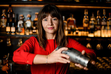 portrait of young beautiful woman bartender with steel shaker in her hands