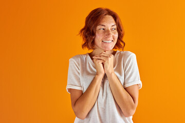 excited lady in casual wear stand in contemplation, dreaming, thinking about something she wish. isolated orange background