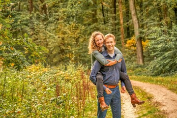 Young couple playing around in the nature, girl sits on the boy's back