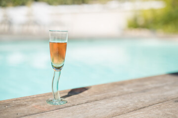 Glass of rosé wine at the edge of a swimming pool